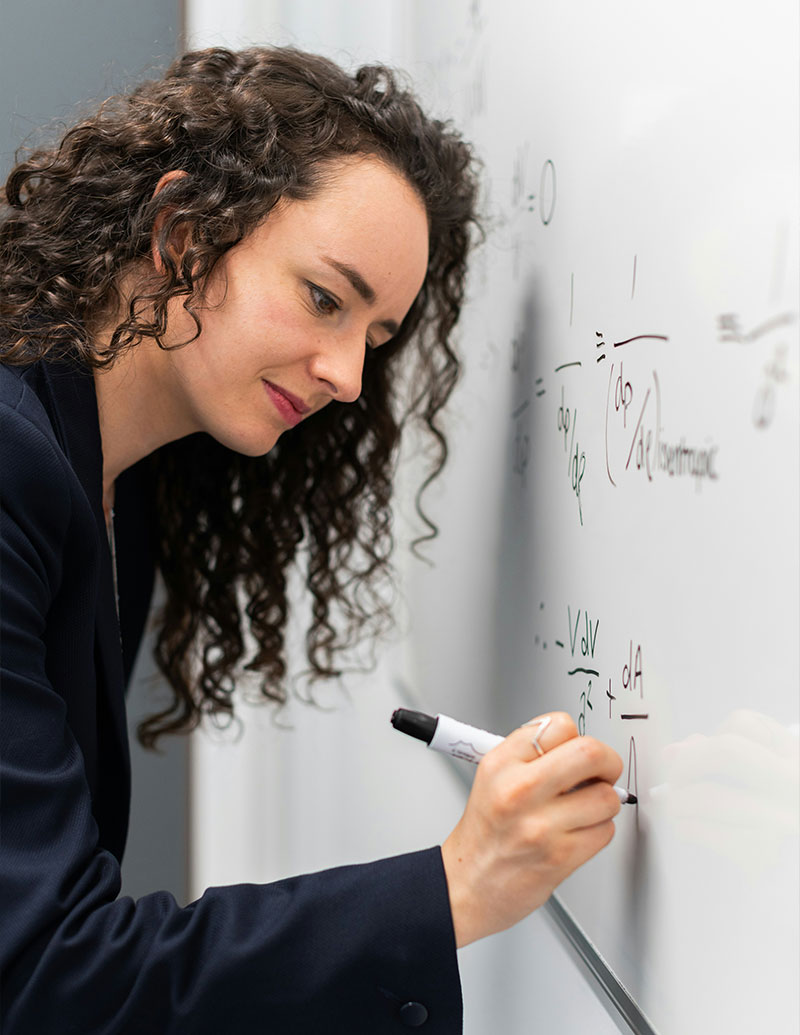 A teacher using markers on a whiteboard roll in a classroom