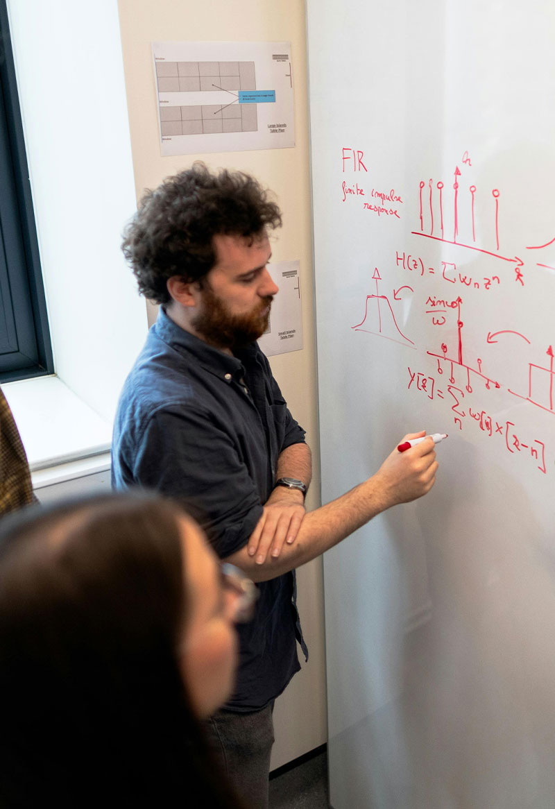 A teacher using markers on a whiteboard roll in a classroom