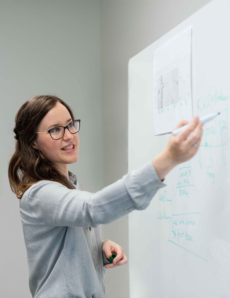 A teacher using markers on a whiteboard roll in a classroom