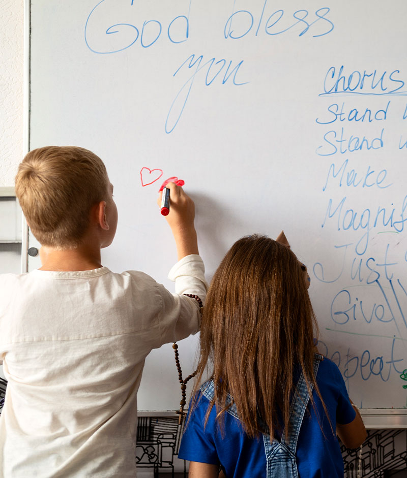 A teacher using markers on a whiteboard roll in a classroom